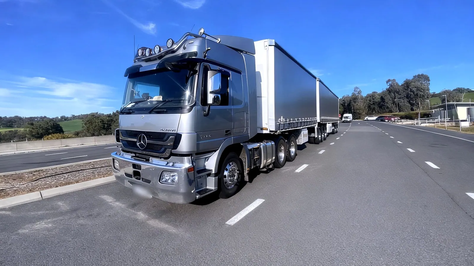 Digiton's silver Mercedes Actros prime mover coupled to a two-trailer B-Double, photographed from the front on a country highway.